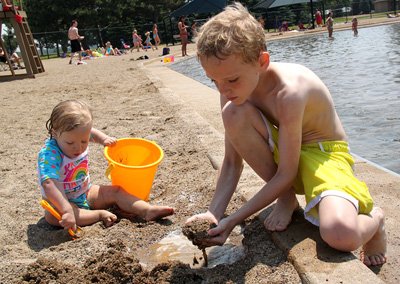 Little girl and boy playing in beach sand