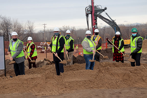 Eight people holding gold shovels of dirt