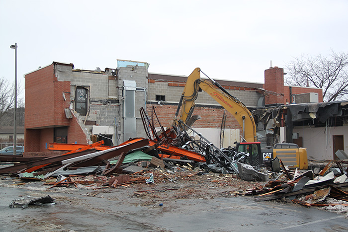 Former city hall building demolished with backhoe