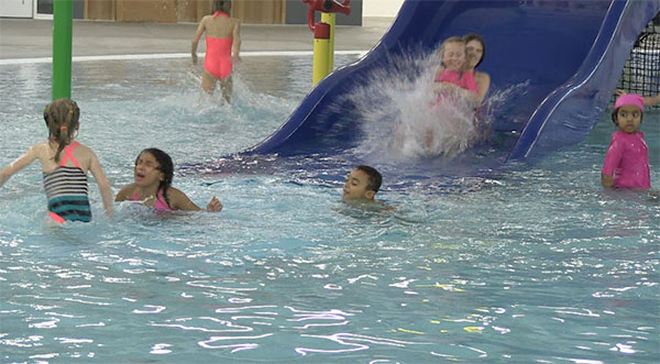 Kids sliding down play feature in pool