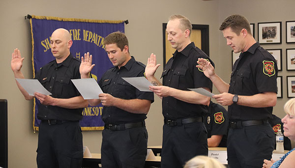 Four firefighters hold hand in arm reading oath of office