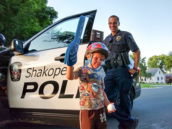 Kid wearing foam finger in front of police car